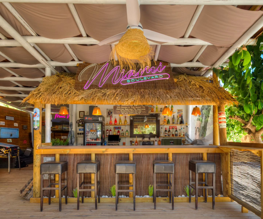 Overdekte bar met rieten dak en barkrukken