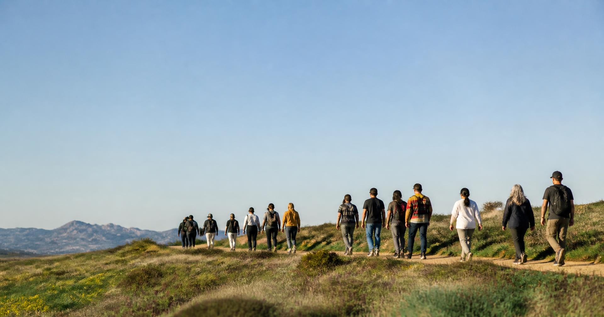 Groep mensen die samen wandelt in een open natuurlandschap met veel lucht